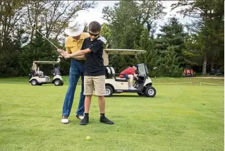  ??  ?? alex Schnee (right) tees off with the help of coach Frank russo. Schnee has been playing for only a year, but has been to all the Mid-atlantic Jbga events.