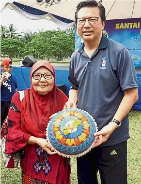  ??  ?? Nice gesture: Che Timah presenting the food cover gift to Liow during his visit to Felda Kampung Sertik in Bentong.