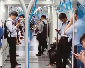  ?? FILE PIC ?? MRT commuters busy looking at their mobile phones in Kuala Lumpur. According to a survey, 69 per cent of Malaysians cannot live without their mobile phones.