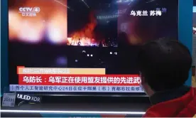  ?? Photograph: AFP/Getty Images ?? A man at a shopping mall in Hangzhou, eastern China, watches a TV screen showing news about the conflict between Russia and Ukraine.