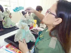  ??  ?? An artisan from the Parañaque Livelihood Resource Management Office shows how delicate embroidery work for one of the sunduan dolls is done.