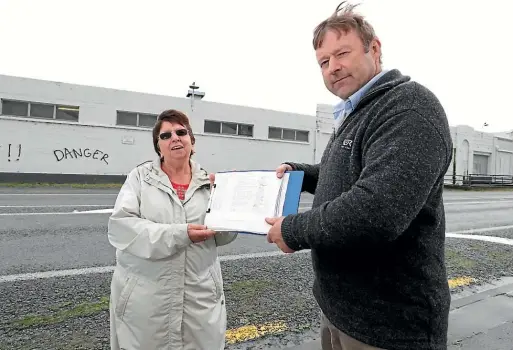  ??  ?? New Zealand First List MP Mark Patterson, right, receives the more than 3000 signature petition from Laurel Turnbull, of Sort Out the Dross action group, outside the closed Mataura paper mill, where the Ouvea premix is being stored. ROBYN EDIE/STUFF
