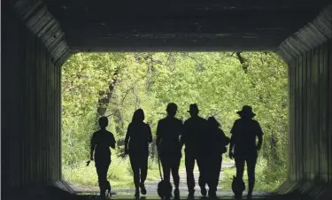  ?? WARREN DILLAWAY — THE STAR-BEACON VIA AP ?? Walkers are silhouette­d on the Greenway Trail in Saybrook Township, in Ashtabula County, on Saturday May 16,