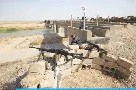  ??  ?? KIRKUK, Iraq: Iraqi forces sit on a river bank across from Kurdish Peshmerga positions yesterday, on the southern outskirts of Kirkuk. —AFP