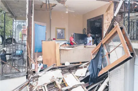  ?? DAVID GRUNFELD/THE ADVOCATE ?? Christophe­r Atkins, left, helps friend George Soloman remove items from his damaged home Monday in New Orleans.