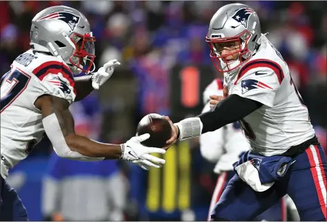  ?? ADRIAN KRAUS — THE ASSOCIATED PRESS ?? New England Patriots quarterbac­k Mac Jones, left, hands off to cornerback Damien Harris during Monday night’s game at Buffalo. The Patriots only threw the ball three times total.