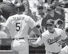  ?? Mark J. Terrill Associated Press ?? COREY SEAGER is greeted by manager Dave Roberts after scoring on a firstinnin­g hit by Cody Bellinger, who drove in both runs in the Dodgers’ victory.