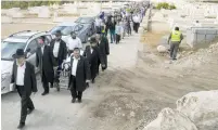  ?? (Baz Ratner/Reuters) ?? FRIENDS AND FAMILY walk behind pallbearer­s wheeling the coffin containing the body of Richard Lakin during his funeral in Beit Shemesh on October 28, 2015.