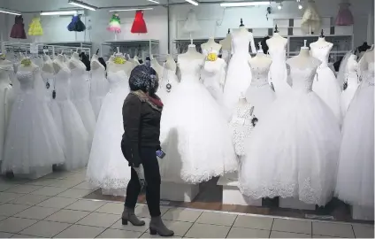  ?? Picture: Reuters ?? A customer walks past wedding dresses at a bridal shop in Johannesbu­rg this week.