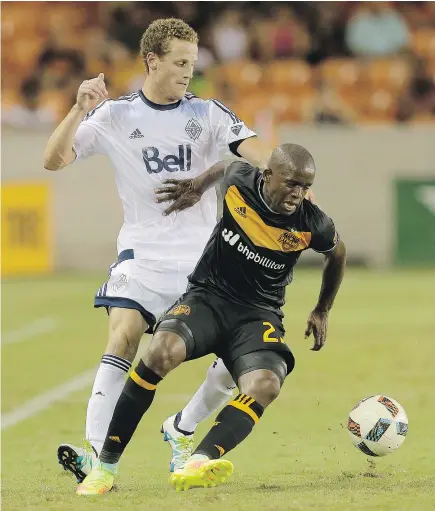  ?? — THE ASSOCIATED PRESS ?? Houston Dynamo midfielder Oscar Garcia, right, fends off Vancouver Whitecaps defender Cole Seiler during the first half of their MLS soccer match Saturday in Houston.