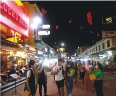  ?? NUTTHAWAT WICHEANBUT ?? People walk down Khao San Road, one of Bangkok’s favourite tourist spots. The government plans to close bars to deal with virus.