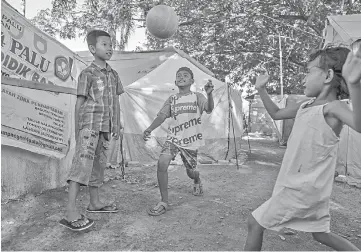  ??  ?? Young quake victim Yuli, 10, (right) playing football with her neighbours at their makeshift camp in Palu, central Sulawesi.