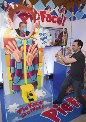  ?? CHARLES SYKES, INVISION FOR HASBRO ?? Hasbro employees play Pie Face Sky High, the standing version of its popular Pie Face game.