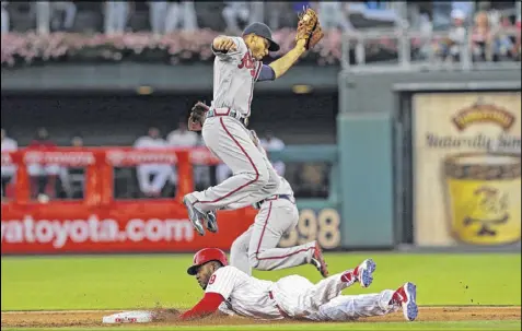  ?? HUNTER MARTIN / GETTY IMAGES ?? Braves shortstop Andrelton Simmons takes the throw as Domonic Brown steals second base in Philadelph­ia’s four-run first inning at Citizens Bank Park. Three of those runs scored on a double by Ryan Howard.