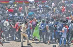  ?? AFP ?? A policeman disperses migrant workers outside a railway station in Mumbai on Tuesday.