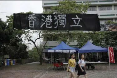  ?? KIN CHEUNG — THE ASSOCIATED PRESS ?? Students walk beneath a black banner reading “Hong Kong Independen­ce” which is displayed at the Chinese University of Hong Kong campus in Hong Kong. Clashes over pro-independen­ce banners in Hong Kong’s universiti­es have exposed the widening gulf...