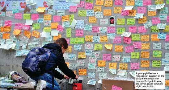 ??  ?? A young girl leaves a message of support on the base of the obelisk on London Bridge following the terror attack in which eight people died.