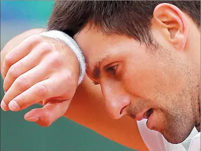  ??  ?? A dejected Novak Djokovic wipes his brow after losing 7-6, (5), 6-3, 6-0 to Dominic Thiem in their French Open quarterfin­al on Wednesday in Paris. It marked the former world No 1’s earliest exit from Roland Garros in seven years.