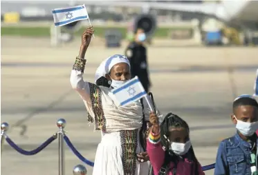  ?? Picture: Amir Levy/Getty Images ?? Newly arrived Jewish Ethiopian immigrants wave the Israeli flag as they walk on a red carpet on landing in Tel Aviv, Israel, on a special flight from Ethiopia.