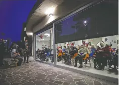  ??  ?? People protected by a glass window attend a Christmas concert at the Martino Zanchi nursing home in Alzano Lombardo, Italy.