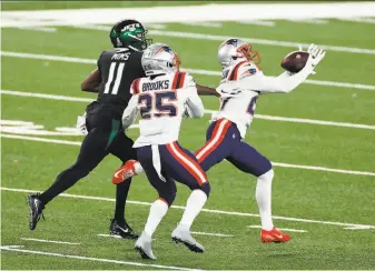  ?? Adam Hunger / Associated Press ?? New England’s J. C. Jackson ( right) makes an intercepti­on in front of Jets wide receiver Denzel Mims in the fourth quarter. The turnover led to the Patriots’ gametying touchdown.