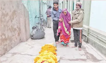  ??  ?? Photo shows Narmadi Devi, 75, being led by relatives to the flower-covered body of her husband Halkey Singh Raghuvansi, outside Salvation House before he was brought to a ghat for cremation in Varanasi.