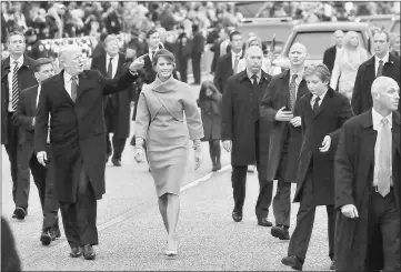  ?? — AFP photos ?? President Trump waves to supporters as he walks the parade route with first lady Melania during the Inaugural Parade on Friday in Washington, DC. Melania (below left) arrives on the West Front of the US Capitol on Friday and (below right) First lady...