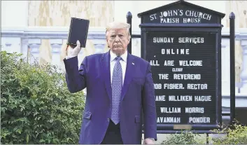  ?? Brendan Smialowski/AFP / TNS ?? President Donald Trump holds up a Bible outside of St John’s Episcopal Church across from Lafayette Park in Washington on Monday.