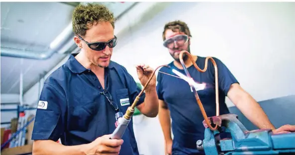 ?? RP-FOTO: ANNE ORTHEN ?? RP-Redakteur Stefan Osorio-König (l.) übt das Löten von Kupferrohr­en unter der Aufsicht von Nicolai Stelzer.