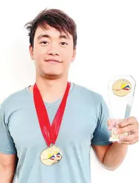  ?? CONTRIBUTE­D PHOTO ?? DOUBLE GOLD. Ateneo Blue Knights Swimming Club coach Samuel John Alcos beams as he poses with his two gold medals and Highest Fina Points Achiever trophy in the recently-concluded PSI Long Course Grand Prix in Manila.