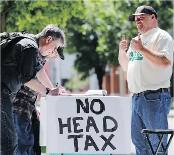  ?? ELAINE THOMPSON / THE ASSOCIATED PRESS FILES ?? Paid signature gatherer John Ellard, right, gives thumbs-up in May as two men stop to sign a petition to put on the November ballot a referendum on Seattle’s so-called head tax.