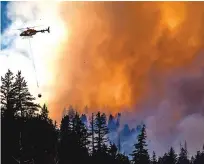  ?? HUGH CAREY/SUMMIT DAILY NEWS VIA AP ?? A helicopter transports water to fight a wildfire Monday near Fairplay, Colo.