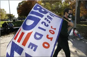  ?? REBECCA BLACKWELL — THE ASSOCIATED PRESS ?? A man carries a flag supporting President- elect Joe Biden during a celebratio­n Sunday in Fairhill Square Park in Philadelph­ia.