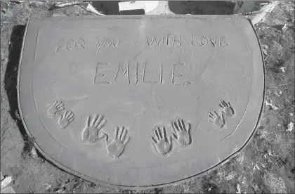  ?? CLOE POISSON/HARTFORD COURANT ?? Freshly poured cement holds handprints and a tribute to Sandy Hook victim Emilie Parker at Emilie’s Shady Spot, a playground built in her memory at the entrance to Riverside Park in New London.