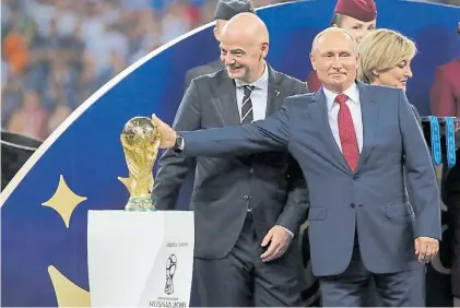  ?? BLOOMBERG. ?? Contento. Vladimir Putin, ayer, toca el trofeo del Mundial ante el jefe de la FIFA, Gianni Infantino.