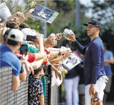  ?? Karen Warren / Staff photograph­er ?? Astros shortstop Carlos Correa greets fans with a smile and autographs during spring training on Monday.