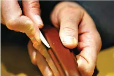  ?? Photos by Brian Elledge/
The Dallas Morning News via AP ?? below left
Wilkinson glues a piece of leather onto a handle for a leather briefcase March 6 in his shop.