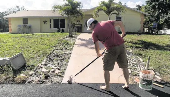  ?? MATIAS J. OCNER mocner@miamiheral­d.com ?? Ray Coulter paints his front walkway on Jan. 31 in West Palm Beach. Coulter and his wife, Kelly, used Ygrene funding to finance a brand new roof and impact windows before Ygrene pulled the financing for everyone in Florida.