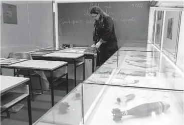  ?? ARMIN DURGUT/AP ?? Arijana Djidelija, a teacher, examines a notebook in a memorial classroom Monday in Sarajevo, Bosnia-Herzegovin­a. Wednesday marked the 30th anniversar­y of Bosnian Serbs laying siege to Sarajevo amid the breakup of Yugoslavia.