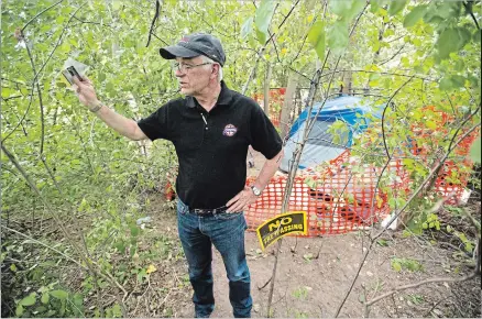  ?? MATHEW MCCARTHY WATERLOO REGION RECORD ?? Vic Rempel stands next to the belongings of a homeless woman who has camped out in a small wooded area near his townhouse complex in Waterloo. People found camping on city property are given seven days’ notice for compassion­ate reasons before being...