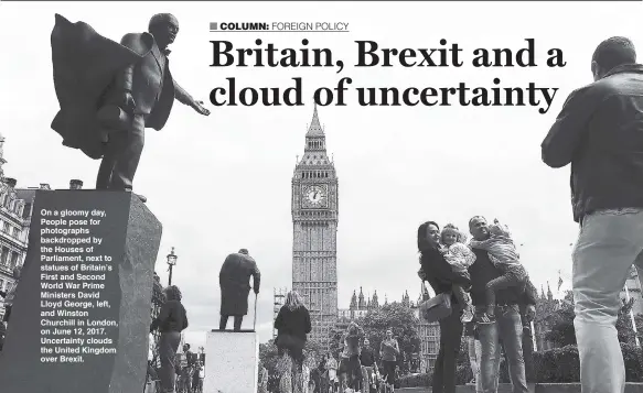  ??  ?? On a gloomy day, People pose for photograph­s backdroppe­d by the Houses of Parliament, next to statues of Britain’s First and Second World War Prime Ministers David Lloyd George, left, and Winston Churchill in London, on June 12, 2017. Uncertaint­y...