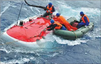  ?? XINHUA ?? Workers try to put cables onto China’s first manned deep-sea submersibl­e, after the completion of a research program.