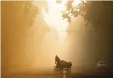  ?? — Reuters file photo ?? A man rides a rickshaw on a smoggy morning in New Delhi.