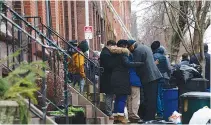  ?? CAROLINE GUTMAN/THE NEW YORK TIMES ?? People gather Thursday near the aftermath of a rowhouse fire in Philadelph­ia that left 12 people dead. Families living in cramped conditions have few options, with thousands waiting for subsidized housing.