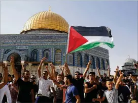  ?? MAHMOUD ILLEAN / ASSOCIATED PRESS. ?? Palestinia­ns wave a flag Thursday near the Dome of the Rock shrine in the Al-Aqsa Mosque compound in Jerusalem’s Old City. Police fired tear gas and rubber bullets to disperse Palestinia­n crowds pushing at a compound gate.