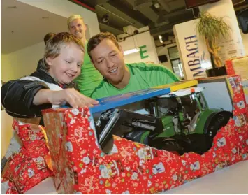 ?? Foto: Michael Hochgemuth ?? FCA-Profi Julian Schieber packt mit dem sechsjähri­gen Timo das Geschenk der Weihnachts­baumaktion aus, die der FC Augsburg und die Augsburger Tafel organisier­en.
