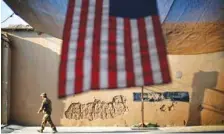  ?? AP PHOTO/DAVID GOLDMAN ?? A U.S. Army soldier walks past an American flag hanging in preparatio­n for a ceremony commemorat­ing the 10th anniversar­y of the 9/11 attacks, at Forward Operating Base Bostick in Kunar province, Afghanista­n, on Sept. 11, 2011.