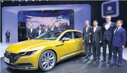  ?? AFP ?? Herbert Diess, CEO of Volkswagen AG, fourth from right, poses with officials and the next generation Volkswagen CC 380 TSI car during its launch at the Beijing Auto Show on Wednesday.