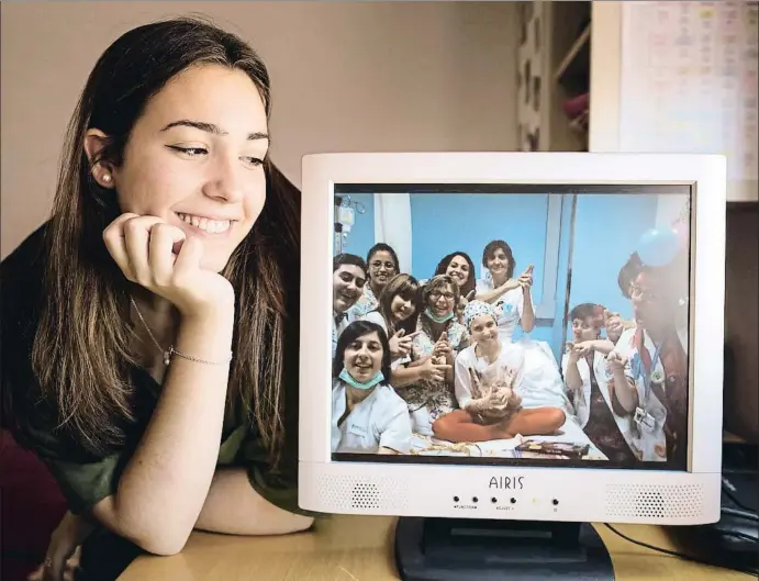  ?? ANA JIMÉNEZ ?? Andrea Tirado mira a la pantalla del seu ordinador la foto del dia que va fer 12 anys, en què es veu envoltada pel personal de l’hospital de Sant Joan de Déu