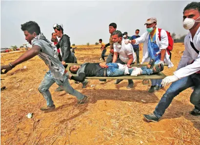  ?? — AFP ?? Wounded by Israeli military gunfire, a Palestinia­n protester is evacuated near the border fence with Israel, in Rafah in southern Gaza Strip, on Friday.